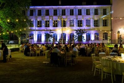 Allée bordée de palmiers éclairés, menant à une fontaine illuminée dans un jardin au crépuscule.
