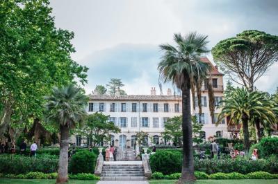 Allée bordée de palmiers éclairés, menant à une fontaine illuminée dans un jardin au crépuscule.