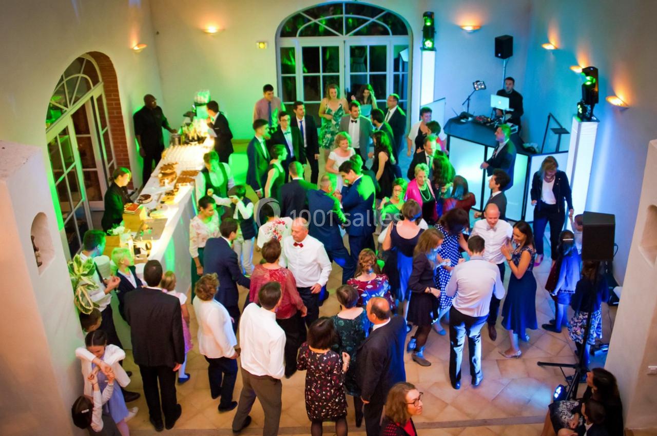 Groupe de personnes dans une salle éclairée, discutant et dansant près d'un bar et d'une piste de danse.