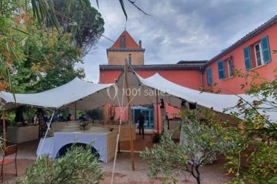 Allée bordée de palmiers éclairés, menant à une fontaine illuminée dans un jardin au crépuscule.