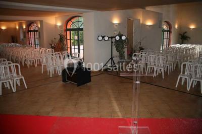 Allée bordée de palmiers éclairés, menant à une fontaine illuminée dans un jardin au crépuscule.