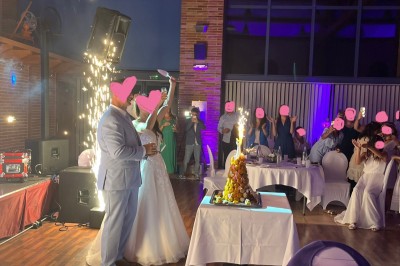 Un couple danse au centre d'une salle de réception éclairée par des lumières colorées et des étincelles.