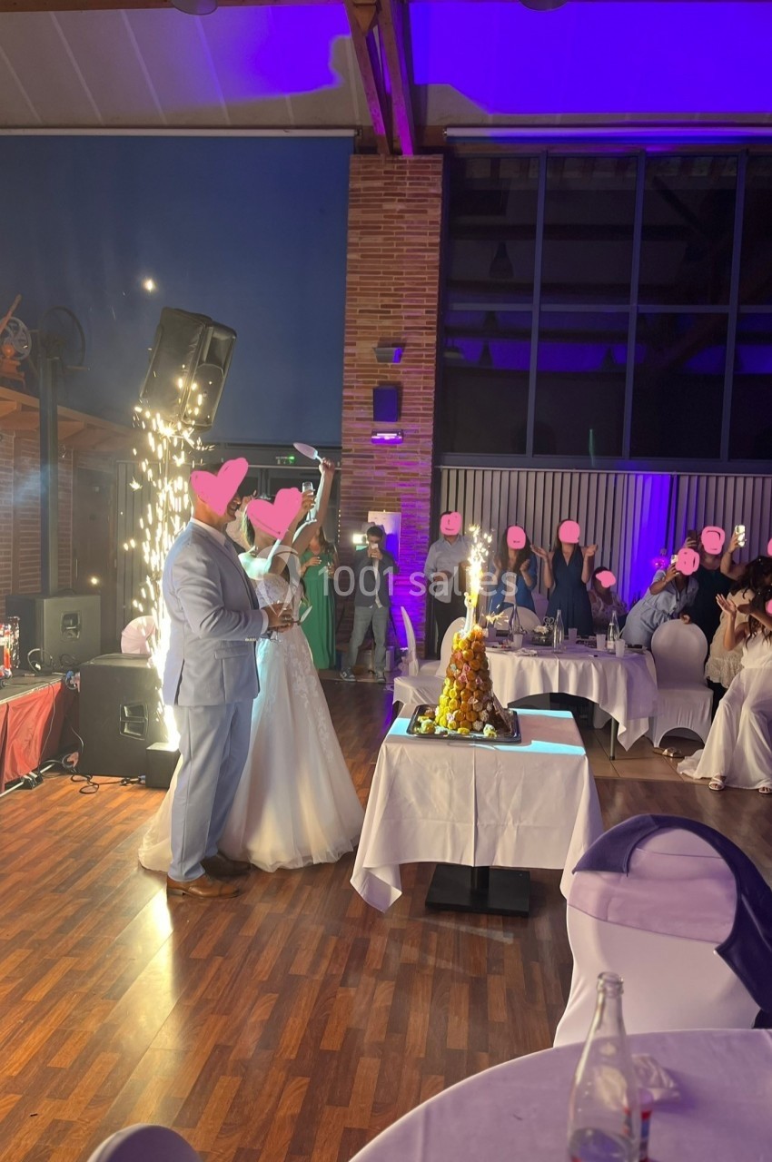 Un couple en tenue de mariage debout près d'une fontaine lumineuse dans une salle de réception décorée.