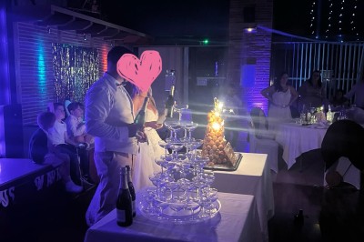 Un couple danse au centre d'une salle de réception éclairée par des lumières colorées et des étincelles.