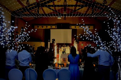 Un couple danse au centre d'une salle de réception éclairée par des lumières colorées et des étincelles.