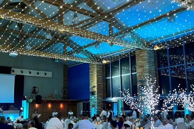 Un couple danse au centre d'une salle de réception éclairée par des lumières colorées et des étincelles.