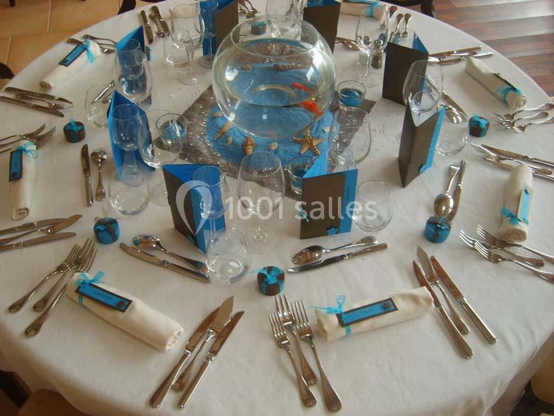 Table dressée avec une décoration marine, comprenant un centre de table avec poissons et des couverts disposés pour…