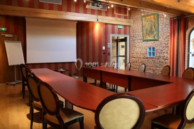 Table de billard en bois avec tapis vert dans une pièce au style rustique, avec poutres apparentes et murs en briques.