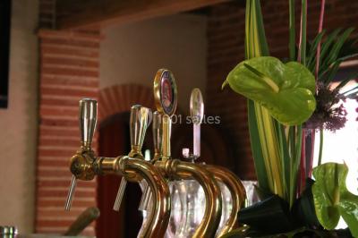 Table de billard en bois avec tapis vert dans une pièce au style rustique, avec poutres apparentes et murs en briques.