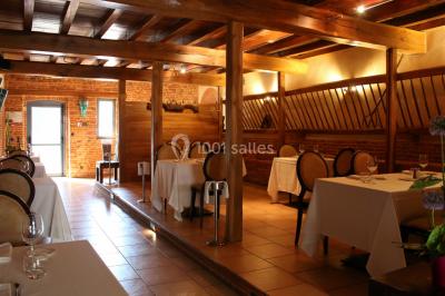 Table de billard en bois avec tapis vert dans une pièce au style rustique, avec poutres apparentes et murs en briques.