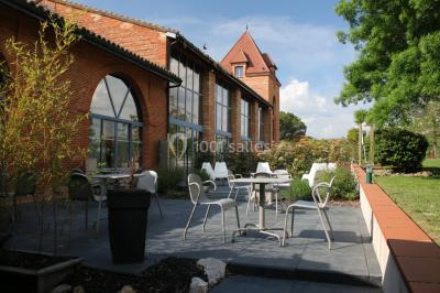 Table de billard en bois avec tapis vert dans une pièce au style rustique, avec poutres apparentes et murs en briques.