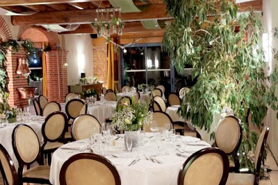 Table de billard en bois avec tapis vert dans une pièce au style rustique, avec poutres apparentes et murs en briques.