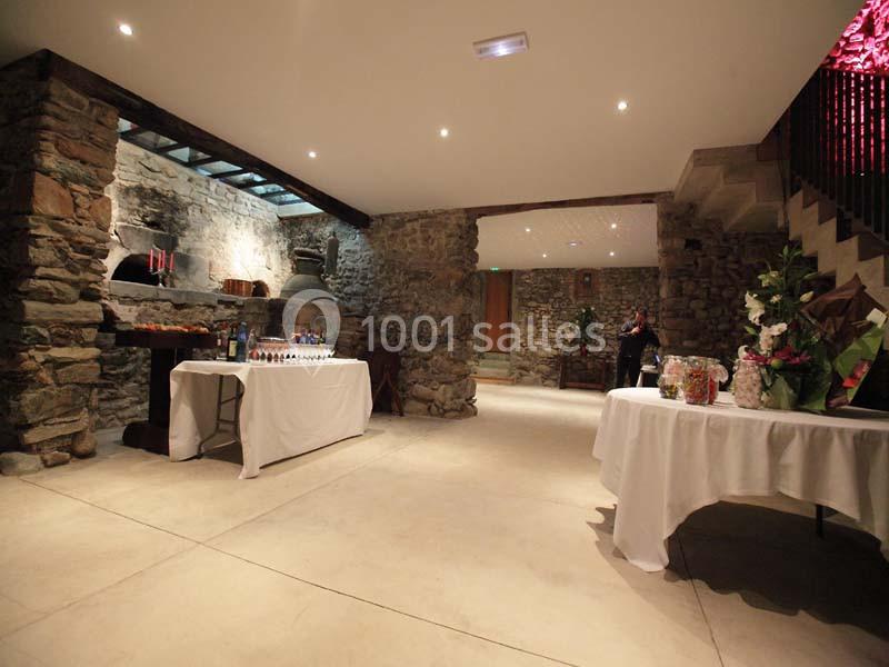 Salle en pierre avec tables dressées pour un buffet, éclairage tamisé et décor rustique.