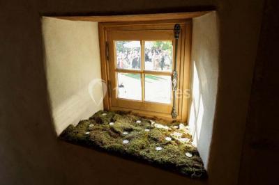 Fenêtre en bois éclairée par la lumière naturelle, avec un rebord recouvert de mousse et de petites bougies.