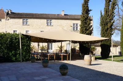 Une mariée en robe blanche marche sur une terrasse en bois, un enfant ajuste son voile sous un ciel dégagé.