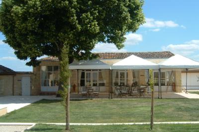 Une mariée en robe blanche marche sur une terrasse en bois, un enfant ajuste son voile sous un ciel dégagé.