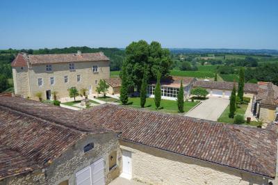 Une mariée en robe blanche marche sur une terrasse en bois, un enfant ajuste son voile sous un ciel dégagé.