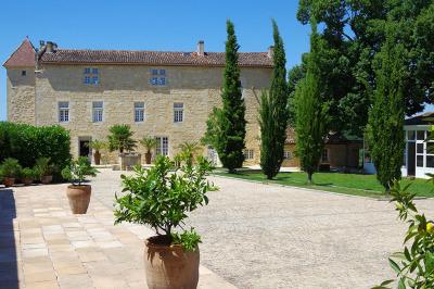 Une mariée en robe blanche marche sur une terrasse en bois, un enfant ajuste son voile sous un ciel dégagé.