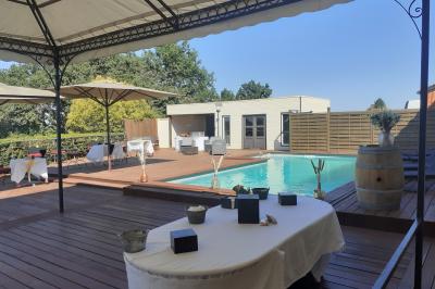 Une mariée en robe blanche marche sur une terrasse en bois, un enfant ajuste son voile sous un ciel dégagé.