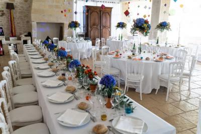 Une mariée en robe blanche marche sur une terrasse en bois, un enfant ajuste son voile sous un ciel dégagé.