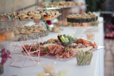 Une mariée en robe blanche marche sur une terrasse en bois, un enfant ajuste son voile sous un ciel dégagé.