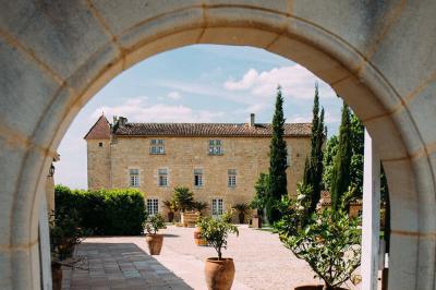 Une mariée en robe blanche marche sur une terrasse en bois, un enfant ajuste son voile sous un ciel dégagé.