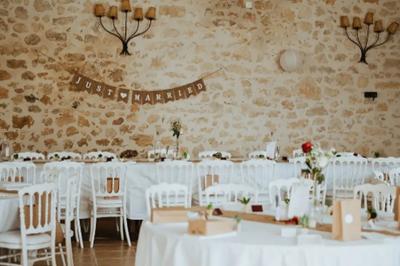 Une mariée en robe blanche marche sur une terrasse en bois, un enfant ajuste son voile sous un ciel dégagé.