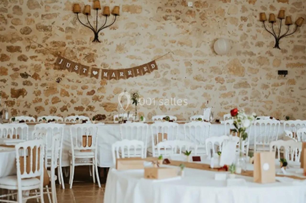 Salle de réception décorée pour un mariage, avec des tables dressées et une bannière ’Just Married’ accrochée au mur en…