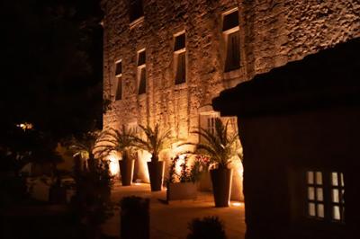 Une mariée en robe blanche marche sur une terrasse en bois, un enfant ajuste son voile sous un ciel dégagé.