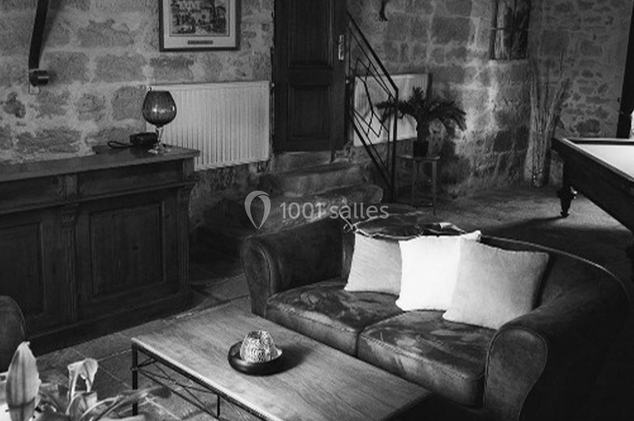 Salon rustique en noir et blanc avec canapé, table basse, meuble en bois et mur en pierre apparente.