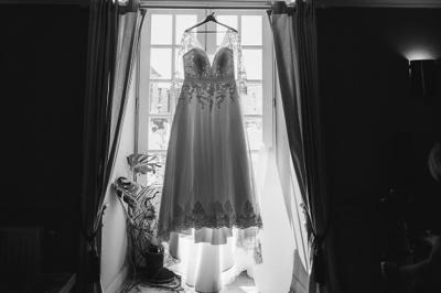 Une mariée en robe blanche marche sur une terrasse en bois, un enfant ajuste son voile sous un ciel dégagé.