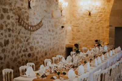 Une mariée en robe blanche marche sur une terrasse en bois, un enfant ajuste son voile sous un ciel dégagé.