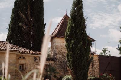 Une mariée en robe blanche marche sur une terrasse en bois, un enfant ajuste son voile sous un ciel dégagé.