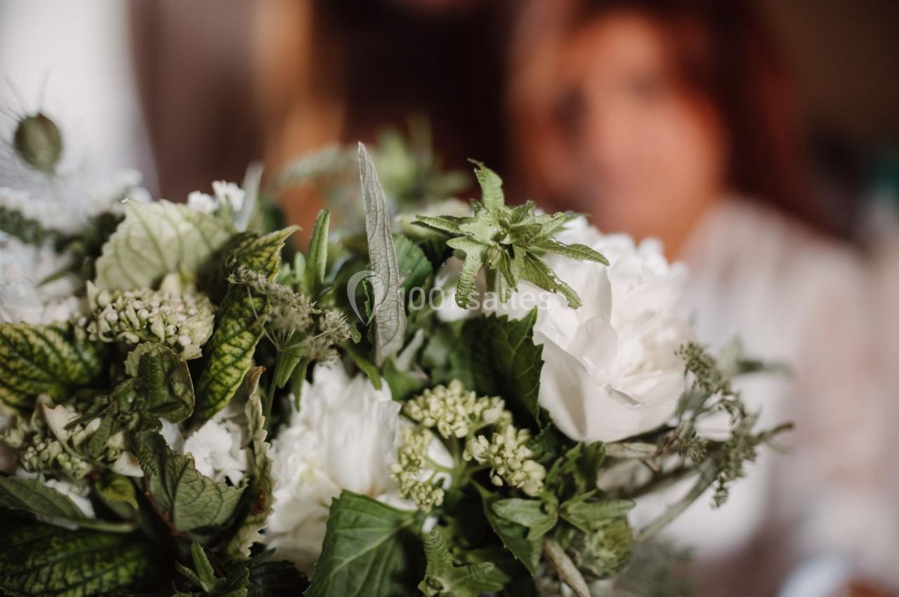 Bouquet de fleurs blanches et vertes avec des feuilles texturées, flou en arrière-plan.