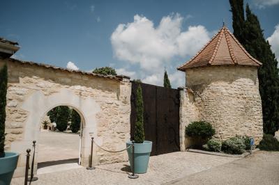Une mariée en robe blanche marche sur une terrasse en bois, un enfant ajuste son voile sous un ciel dégagé.