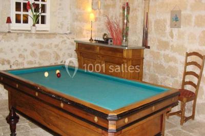 Rangées de fûts en bois alignés dans une cave en pierre éclairée par des lumières chaudes.