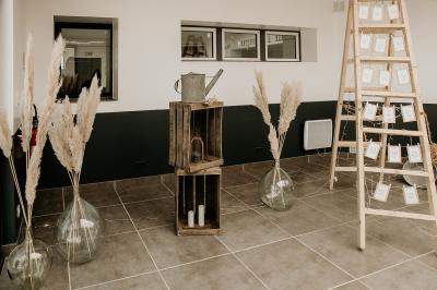 Salle de réception décorée avec des tables dressées, nappes blanches, chemins de table en jute et chaises noires.