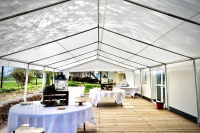 Salle de réception décorée avec des tables dressées, nappes blanches, chemins de table en jute et chaises noires.