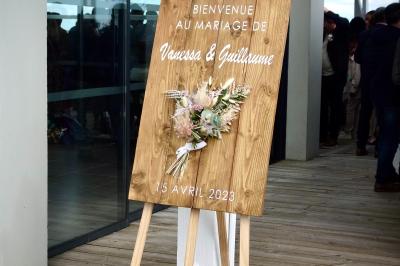 Salle de réception décorée avec des tables dressées, nappes blanches, chemins de table en jute et chaises noires.
