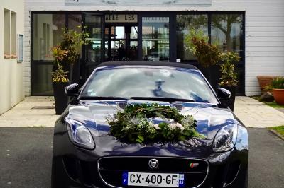 Salle de réception décorée avec des tables dressées, nappes blanches, chemins de table en jute et chaises noires.