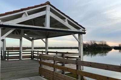 Salle de réception décorée avec des tables dressées, nappes blanches, chemins de table en jute et chaises noires.