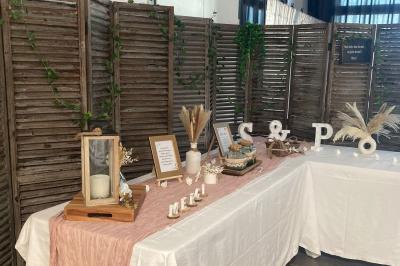 Salle de réception décorée avec des tables dressées, nappes blanches, chemins de table en jute et chaises noires.