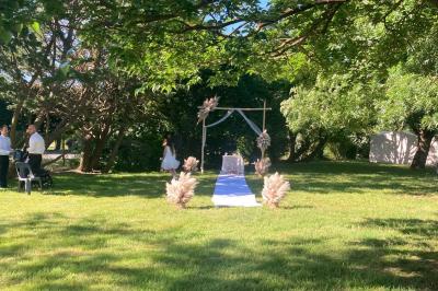 Salle de réception décorée avec des tables dressées, nappes blanches, chemins de table en jute et chaises noires.