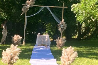 Salle de réception décorée avec des tables dressées, nappes blanches, chemins de table en jute et chaises noires.