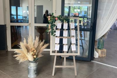 Salle de réception décorée avec des tables dressées, nappes blanches, chemins de table en jute et chaises noires.