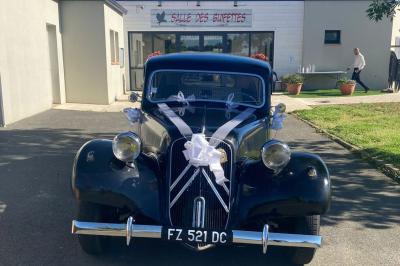 Salle de réception décorée avec des tables dressées, nappes blanches, chemins de table en jute et chaises noires.