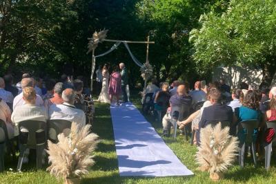 Salle de réception décorée avec des tables dressées, nappes blanches, chemins de table en jute et chaises noires.