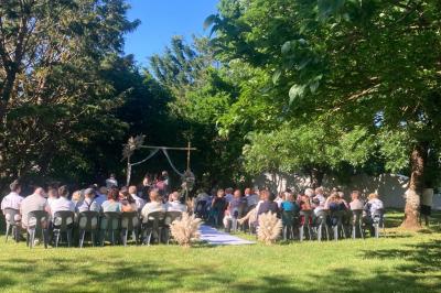 Salle de réception décorée avec des tables dressées, nappes blanches, chemins de table en jute et chaises noires.