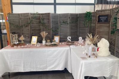Salle de réception décorée avec des tables dressées, nappes blanches, chemins de table en jute et chaises noires.