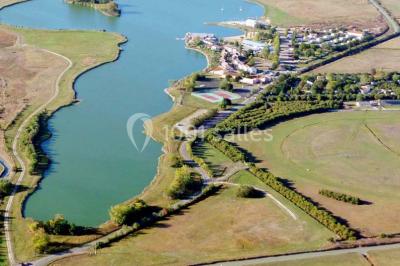 Terrain de mini-golf en plein air avec pelouse, arbres et parcours délimités par des bordures colorées.